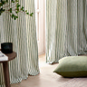 close up on bottom of green striped curtains, lightly brushing wooden floor