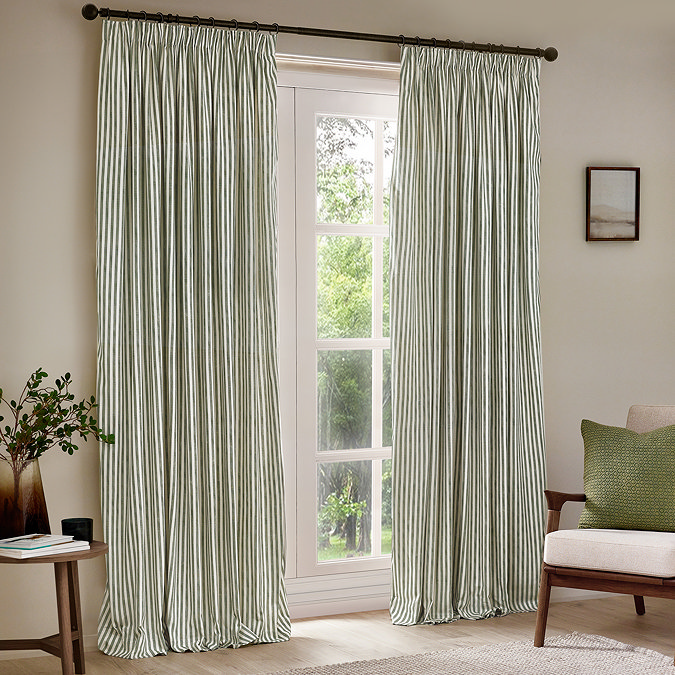 image of a pair of light green striped cotton curtains hanging, open, in front of a floor length living room window