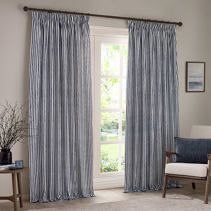 navy blue cotton striped curtains open across a floor length living room window