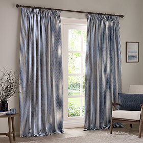 navy blue cotton striped curtains open across a floor length living room window