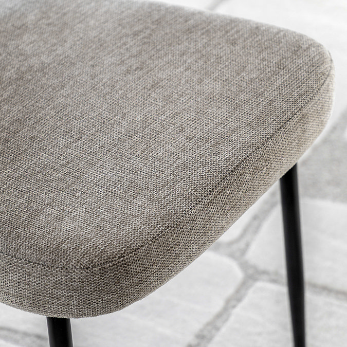 close up on natural fabric of dining chair with black metal legs