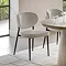 image of natural coloured upholstered dining chair with black legs and slightly curved back, on a marble floor