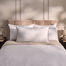 king size silentnight hotel pillow, leaning against two smaller pillows behind on a bed