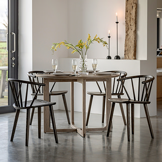 image of round smoked oak dining table with four dark brown wooden chairs
