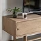 close up image of left drawer of tv unit with small cut-out handle and faux plant on top of smooth oak surface