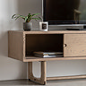 close up on smoked oak tv unit with slim drawers, left drawer slid open to reveal slim magazines stacked inside