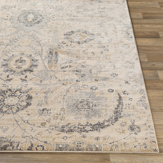 close up image of corner of beige floral rug laid flat on wooden flooring