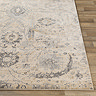 close up image of corner of beige floral rug laid flat on wooden flooring