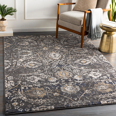 image of black rug with beige and grey floral pattern, folded slightly to reveal material underneath