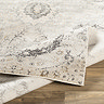 image of grey and ivory patterned rug folded over slightly to suggest thinness