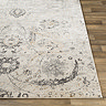 close up image of corner of ivory rug with grey pattern laid flat on wood flooring