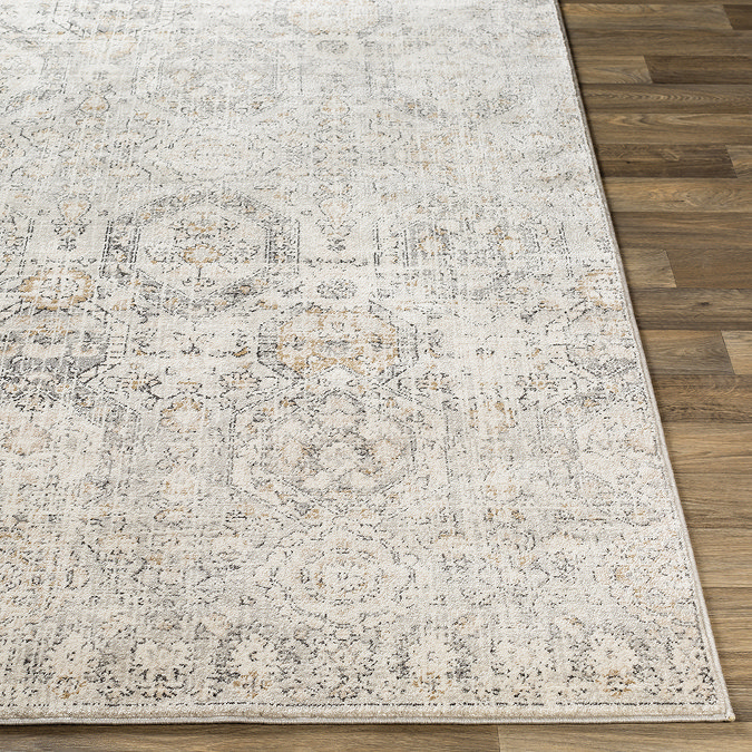 close up image of front of vintage rug with grey pattern laid flat on wood flooring
