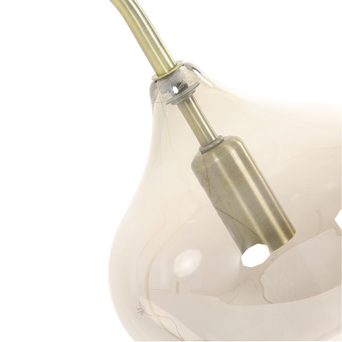 close up image cut out on white background of smoked glass table lamp, showing where antique bronze light goes into the flower-bud shaped glass shade