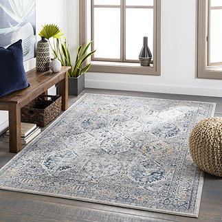 image of vintage grey-blue patterned rug on dark wood living room floor in front of side table and windows with light streaming through