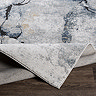 image of grey-blue abstract rug folded over slightly to suggest its thickness