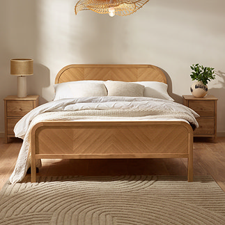 image of wooden bed with chevron pattern, decorated with mattress, duvet cover, and in warm lighting