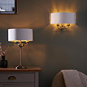 wider image of two arm wall light on wall with matching brass table lamp on dressing table next to it