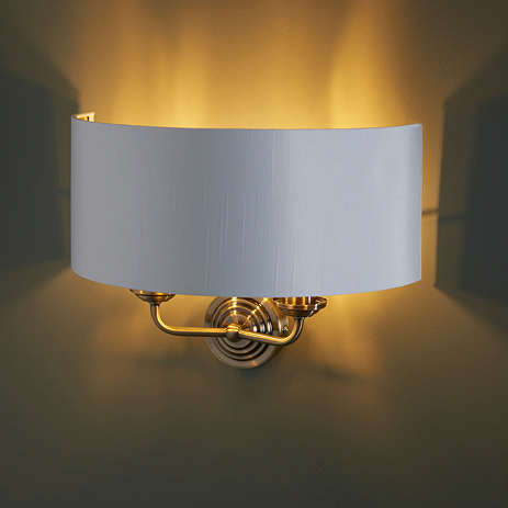 image of two arm light with antique brass arms on dark wall emitting a warm glow