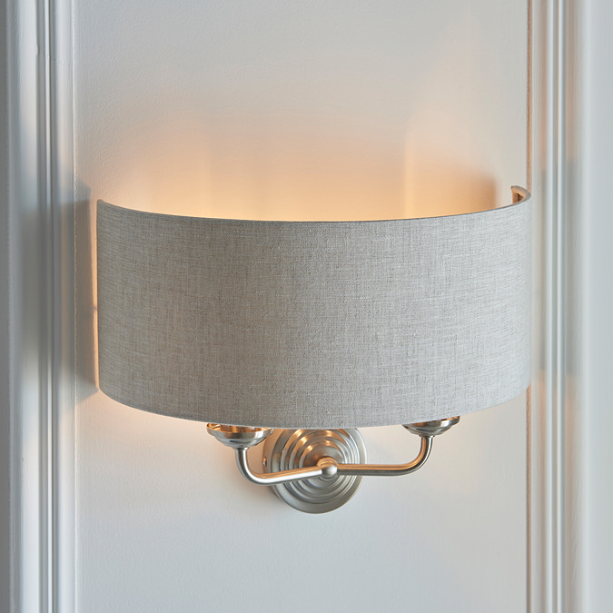 side image of curved fabric wall lamp with 2 chrome arms on a white wall