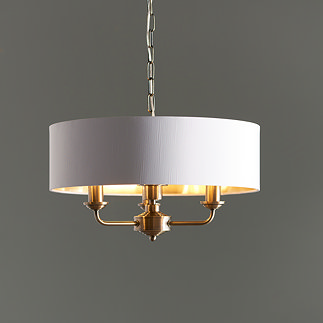 image of antique brass pendant light with white shade hanging in front of mid-grey wall