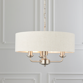 image of 3 arm pendant ceiling light with beige shade and chrome bodywork hanging from ceiling in front of cream wall