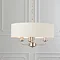 image of 3 arm pendant ceiling light with beige shade and chrome bodywork hanging from ceiling in front of cream wall
