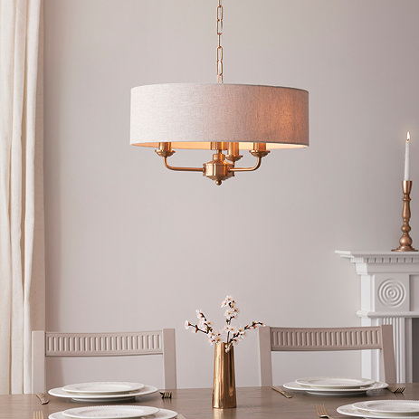 image of vintage brass three arm pendant light with natural shade over a dining room table