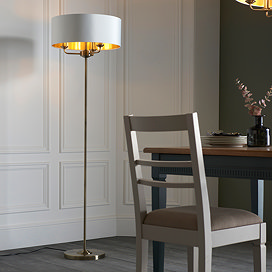 image of antique lamp with dark brass body and white linen shade, stood at the end of a dark oak dining table