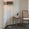 image of tall thin floor lamp with grey shade and nickel body, stood in corner of dining room emitting warm glow