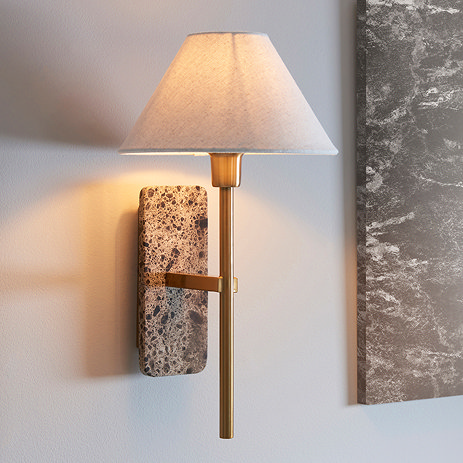 image of thin brass-toned wall light with tapered shade and brown marble backplate