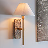 image of thin brass-toned wall light with tapered shade and brown marble backplate