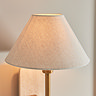 close up image of tapered linen shade of thin brass coloured wall light