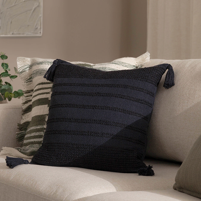 image of square black cushion with subtle textured stripes and tasselled edges
