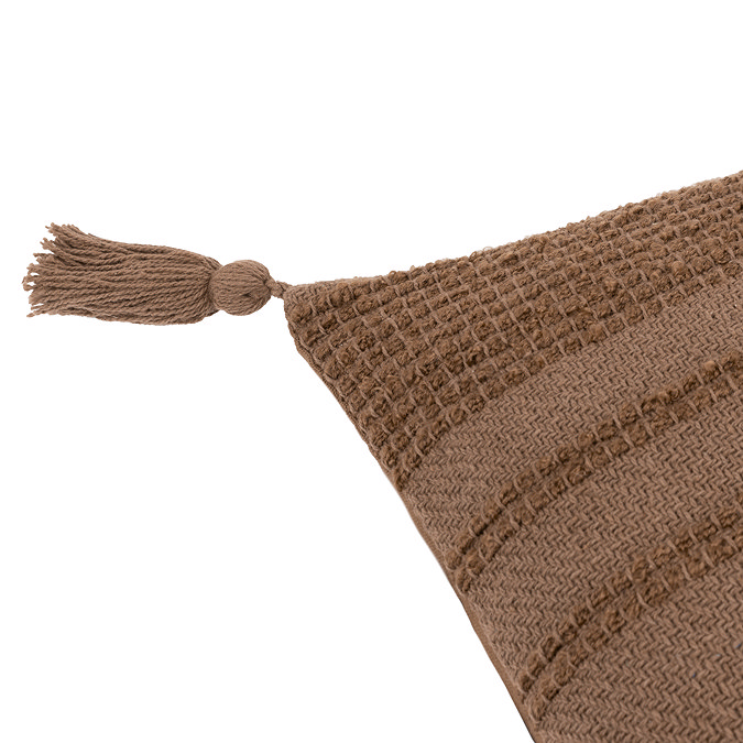 close up on tasselled corner of warm brown textured cushion