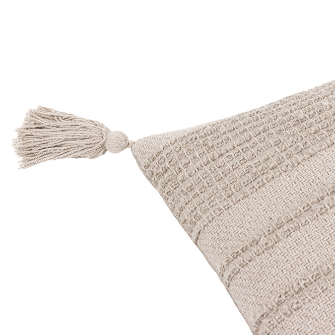 image cut out on white background of stone coloured cushion with tasselled corner