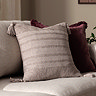 image of stone coloured textured cushion with tasselled corners, on natural sofa in front of burgundy cushion