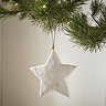 close up on a large white wood star, hanging from a christmas tree