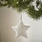 close up on a large white wood star, hanging from a christmas tree
