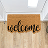 image of shaped welcome mat on wooden flooring in front of white door