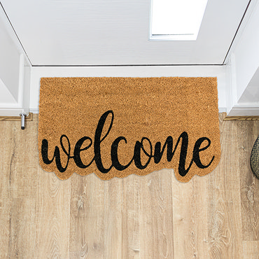 image cut out on white background of doormat with edge cut out to the shape of word 'welcome' in black
