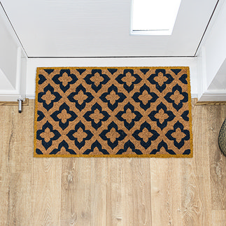 image of rectangular natural doormat with diamond pattern and mustard border, on wooden flooring in front of white door