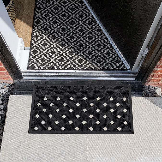 image of black and white latticed rubber scraper mat in front of door