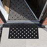 image of black and white latticed rubber scraper mat in front of door