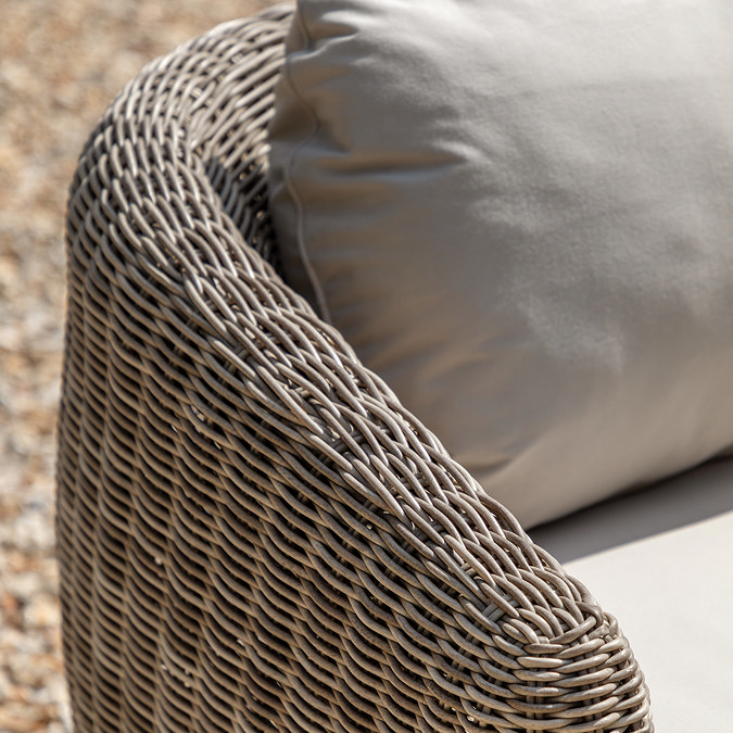close up on rattan sides of outdoor sofa with plush cream cushions