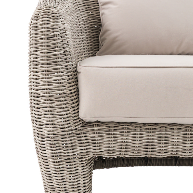 image cut out on white background of rattan sofa with plush cream cushions, focus close up on texture of materials