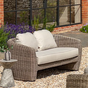 close up on rattan sides of outdoor sofa with plush cream cushions