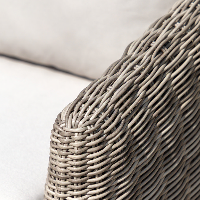 close up image of rattan frame and plush cream cushion of garden armchair