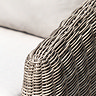 close up image of rattan frame and plush cream cushion of garden armchair