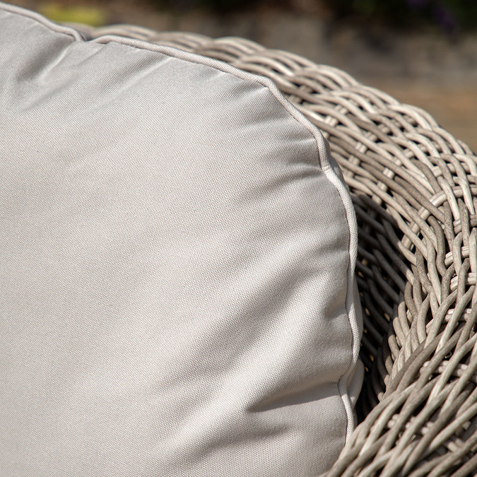 close up on cream cushion of garden armchair with rattan curved back
