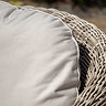 close up on cream cushion of garden armchair with rattan curved back